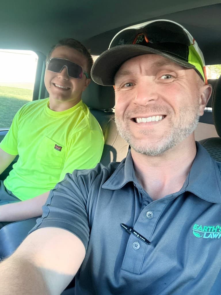 Jacob Lewis, owner of Earth's Way Lawncare, with his son on the job